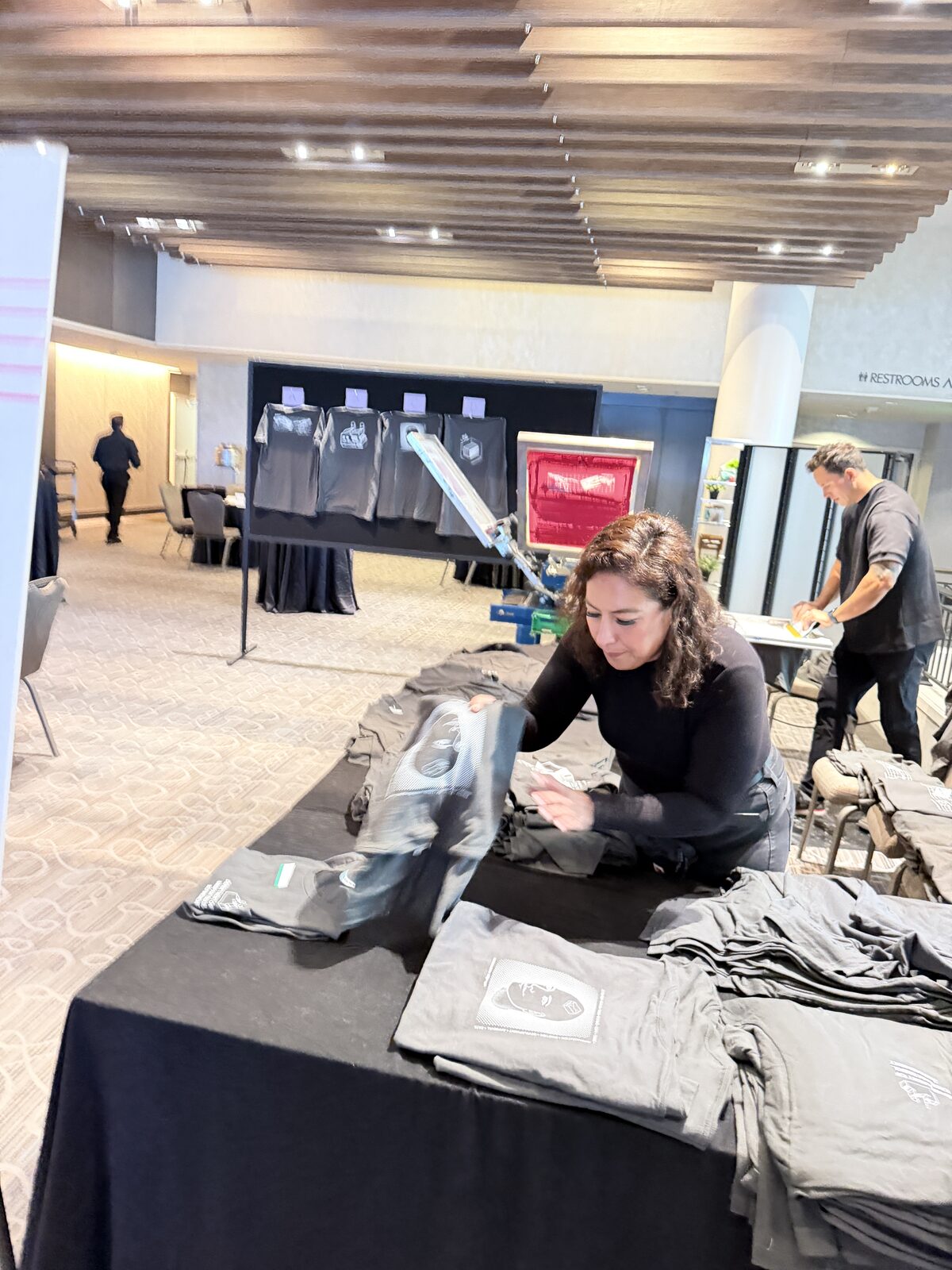 Merch Troop staff folding freshly printed shirts at a corporate event table