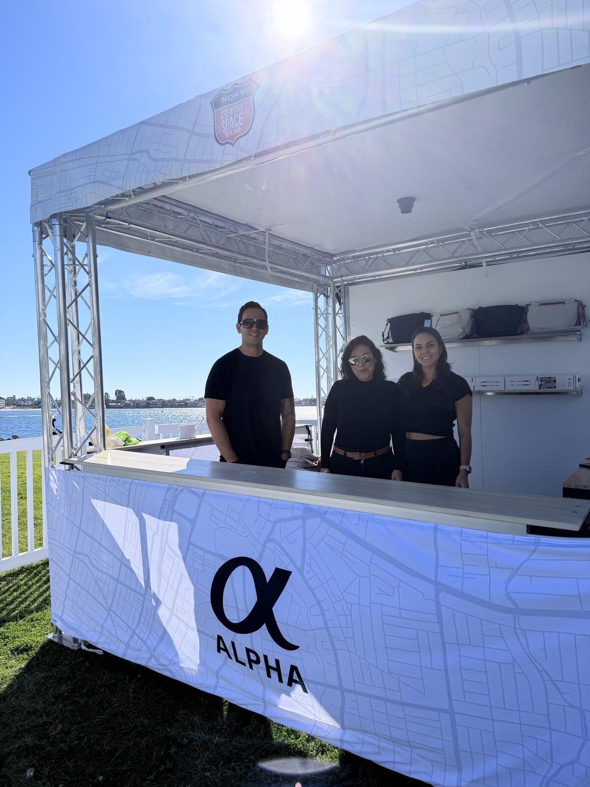 Branded outdoor swag booth staffed by a printing crew at a waterfront company event